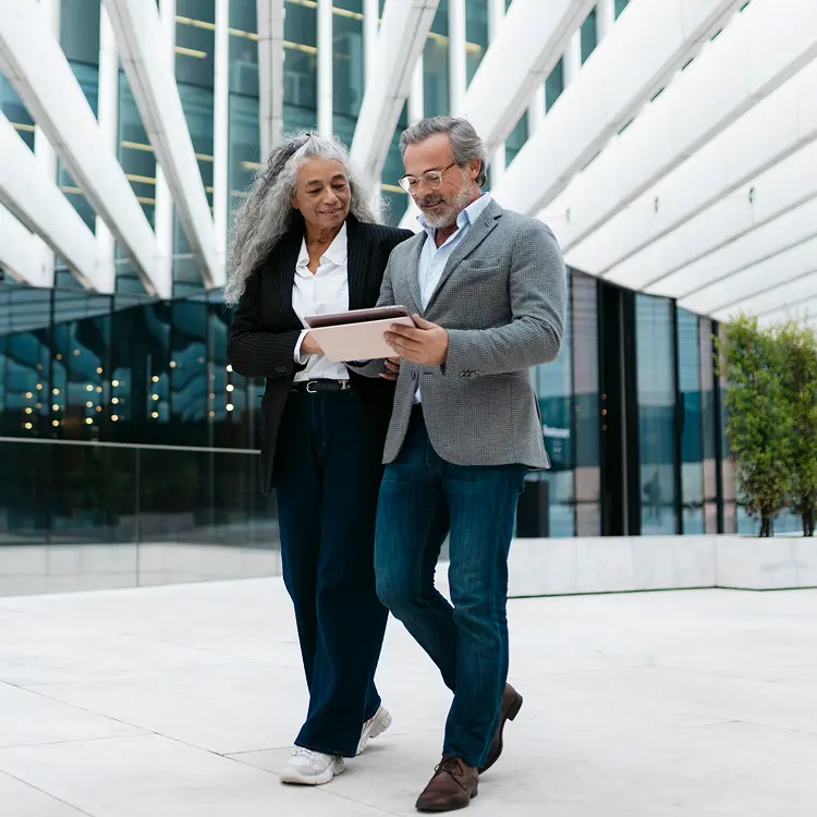 Woman and man reviewing ipad while walking outside of office building
